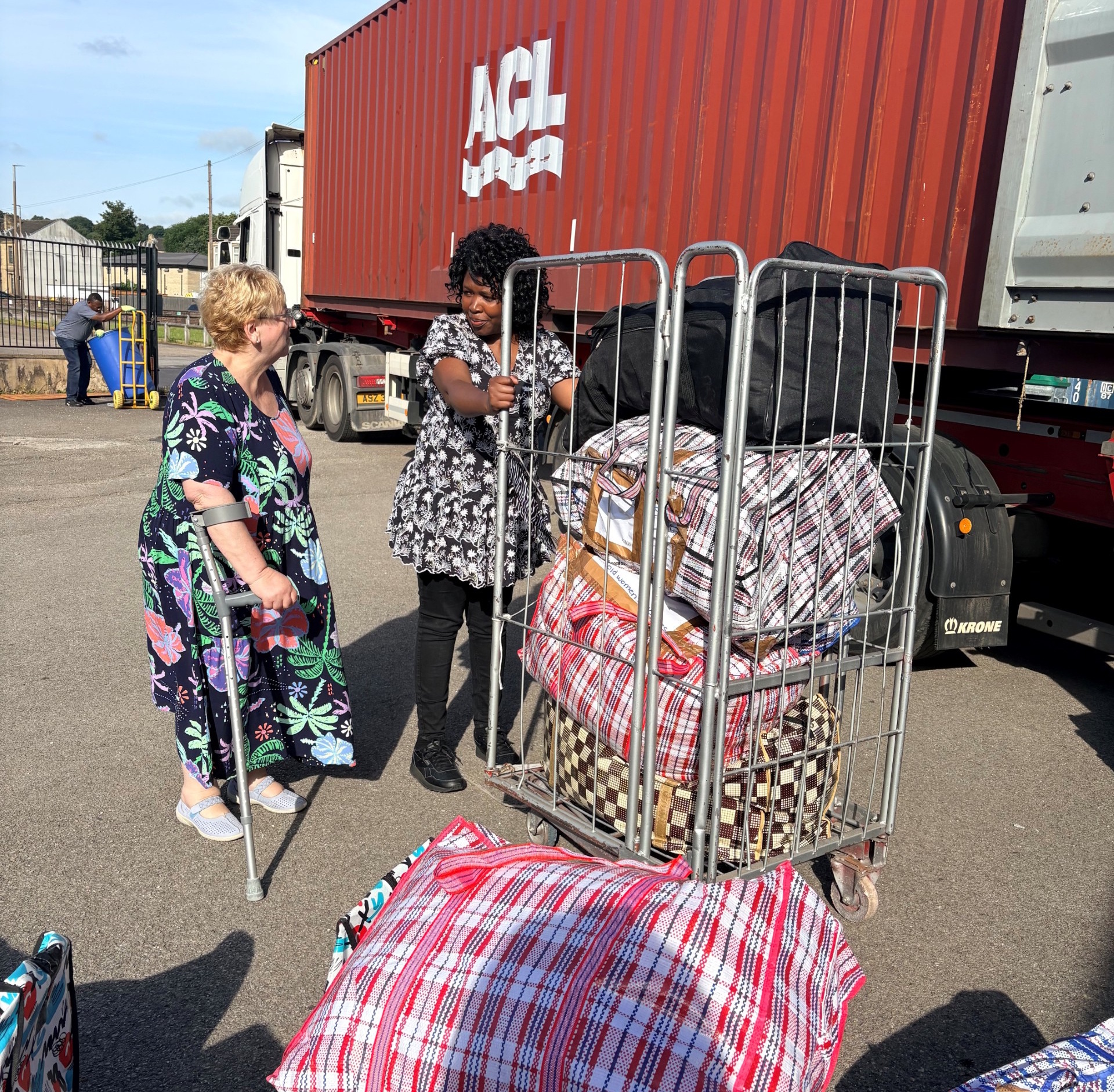 Supporters wheeling a trolley of laundry bags and bundles alongside the container