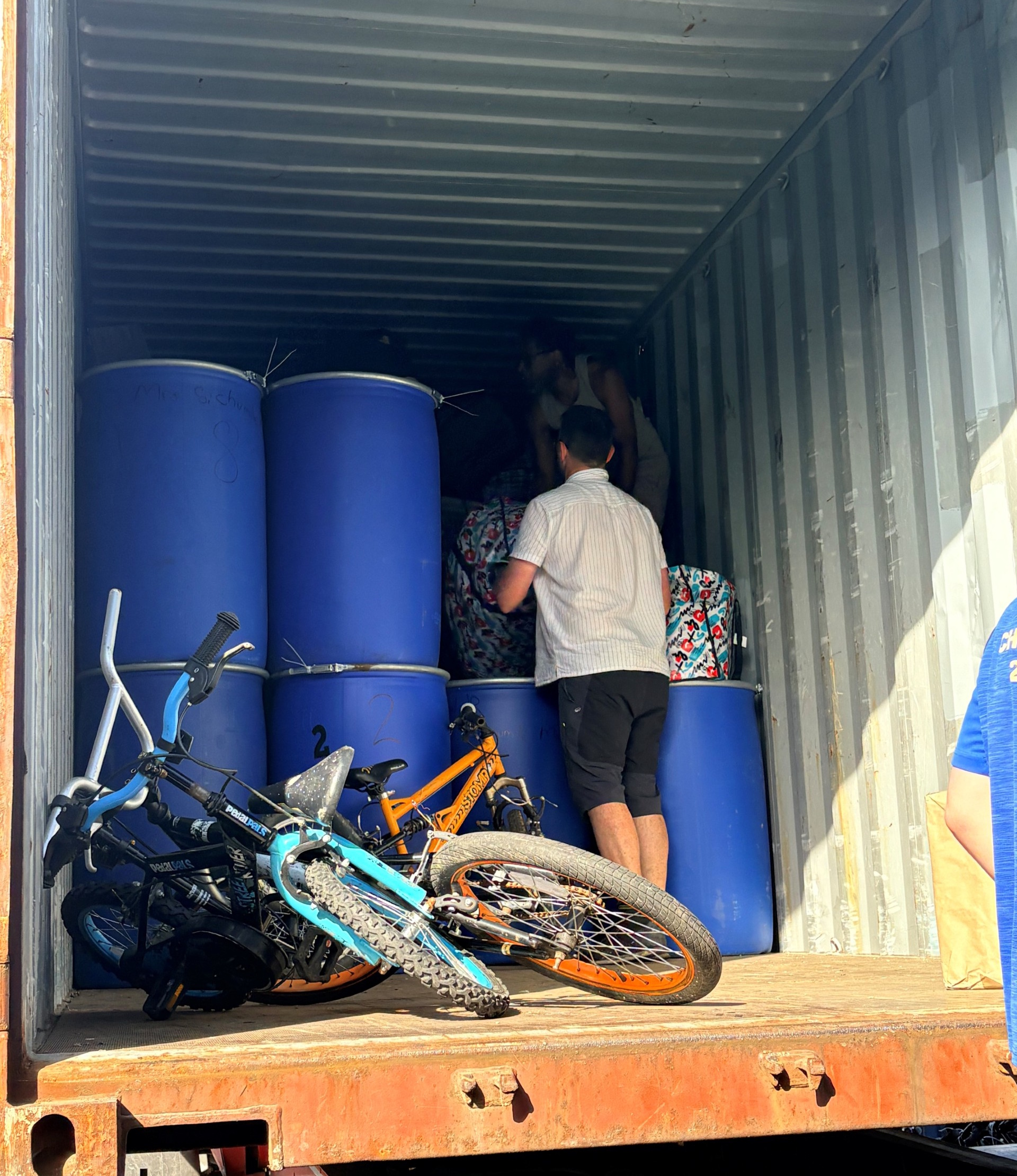 Inside the container: blue storage barrels and donated bicycles packed for the journey